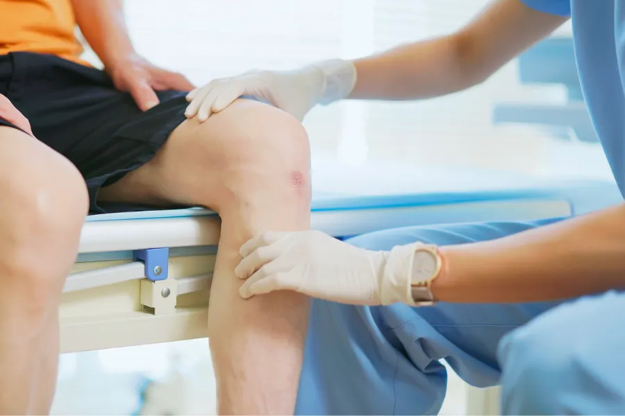 Doctor assisting patient with knee