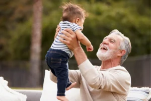 Grandfather lifting grandchild comfortably after successful shoulder pain treatment